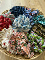 Assorted colorful fabric scrunchies in a woven basket on a wooden surface