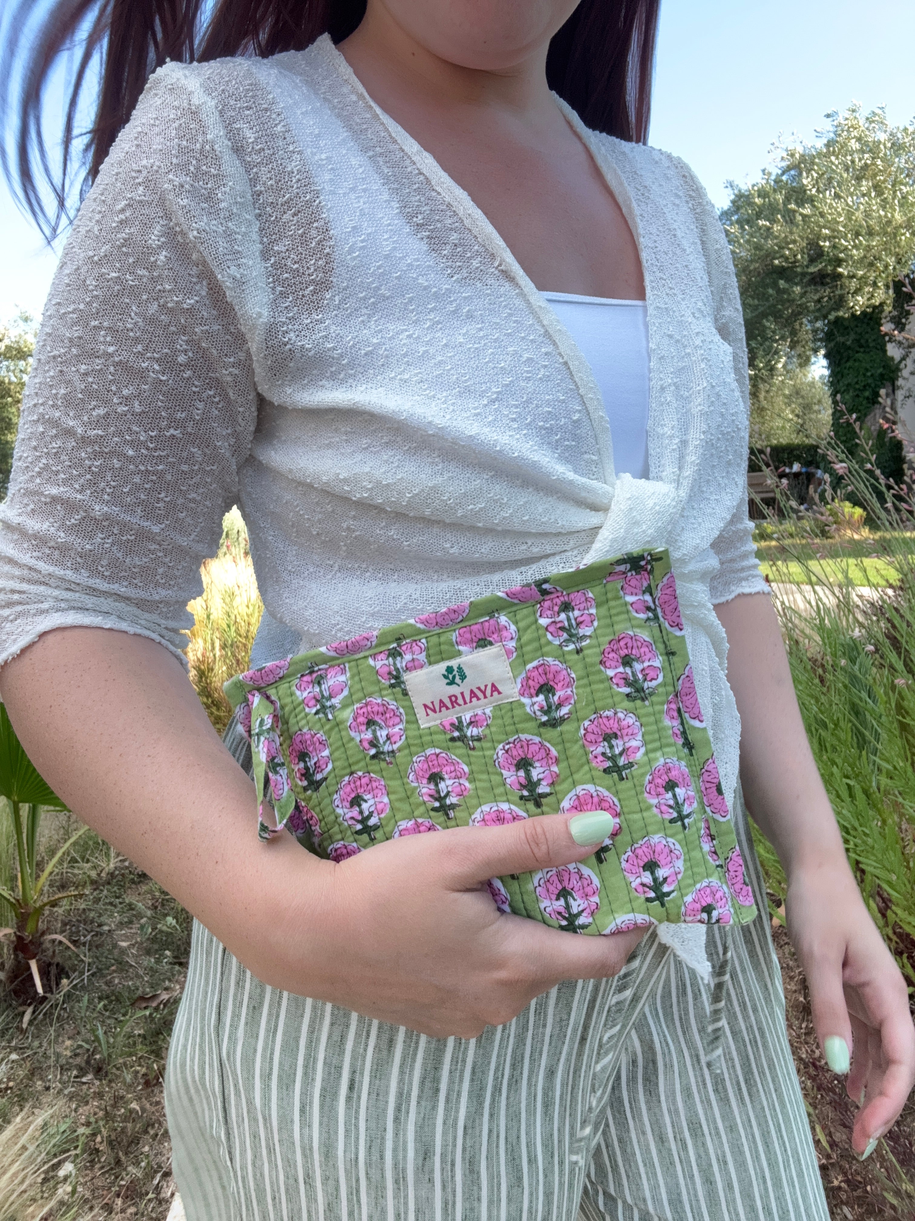 Person holding a green and pink patterned bag outdoors