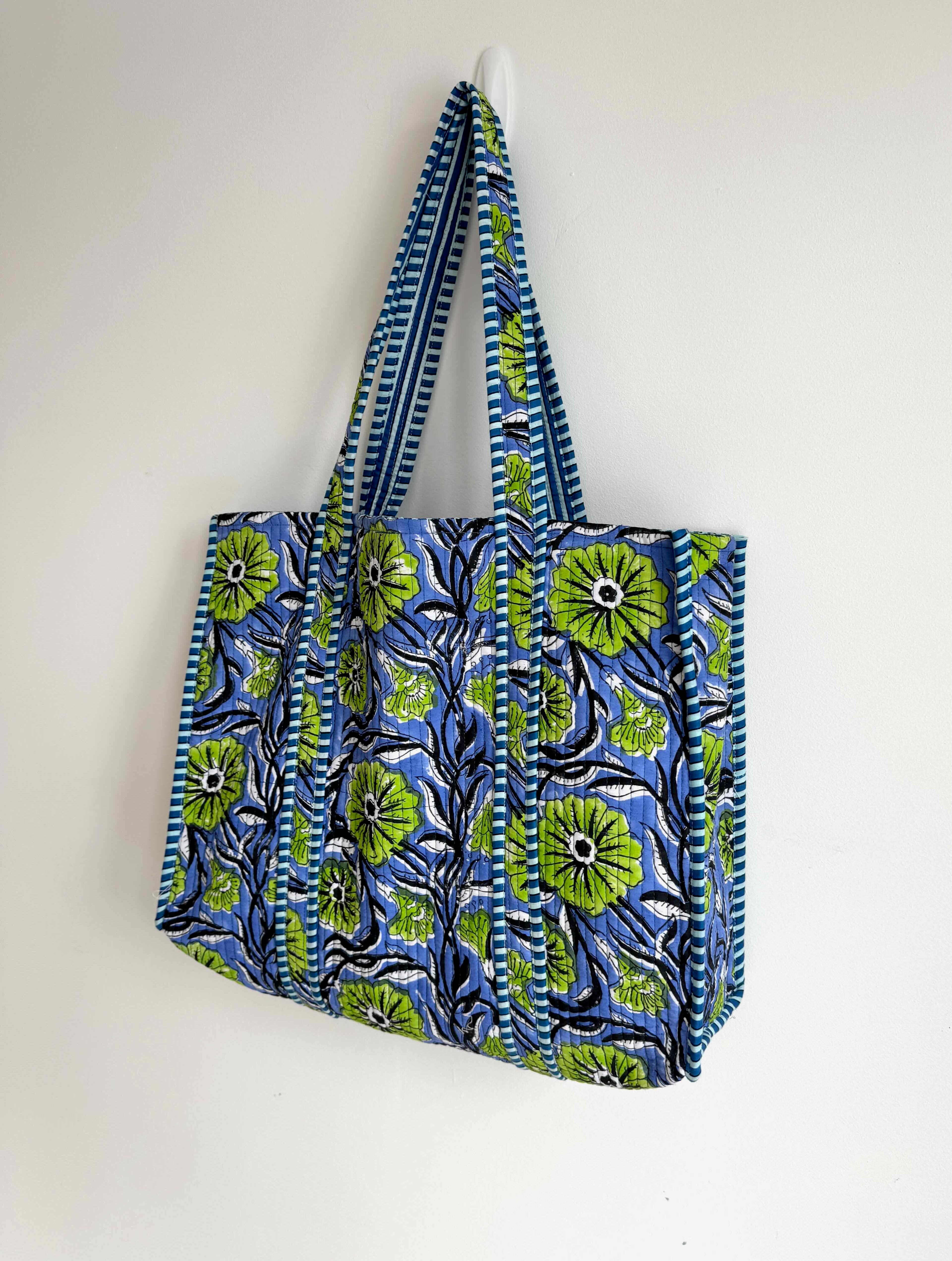 Blue and green patterned tote bag hanging on a white wall