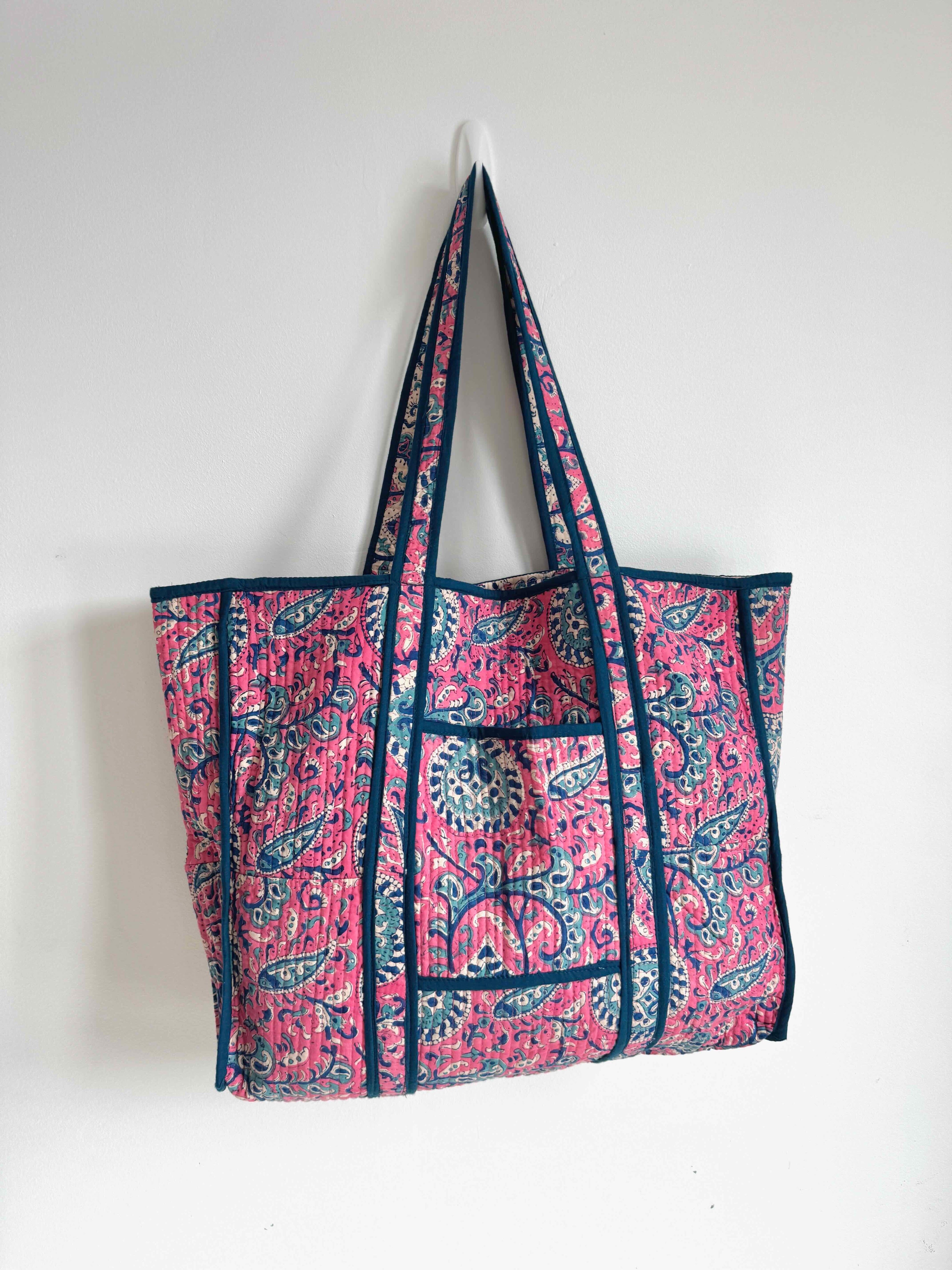 Pink and blue patterned tote bag hanging on a white wall
